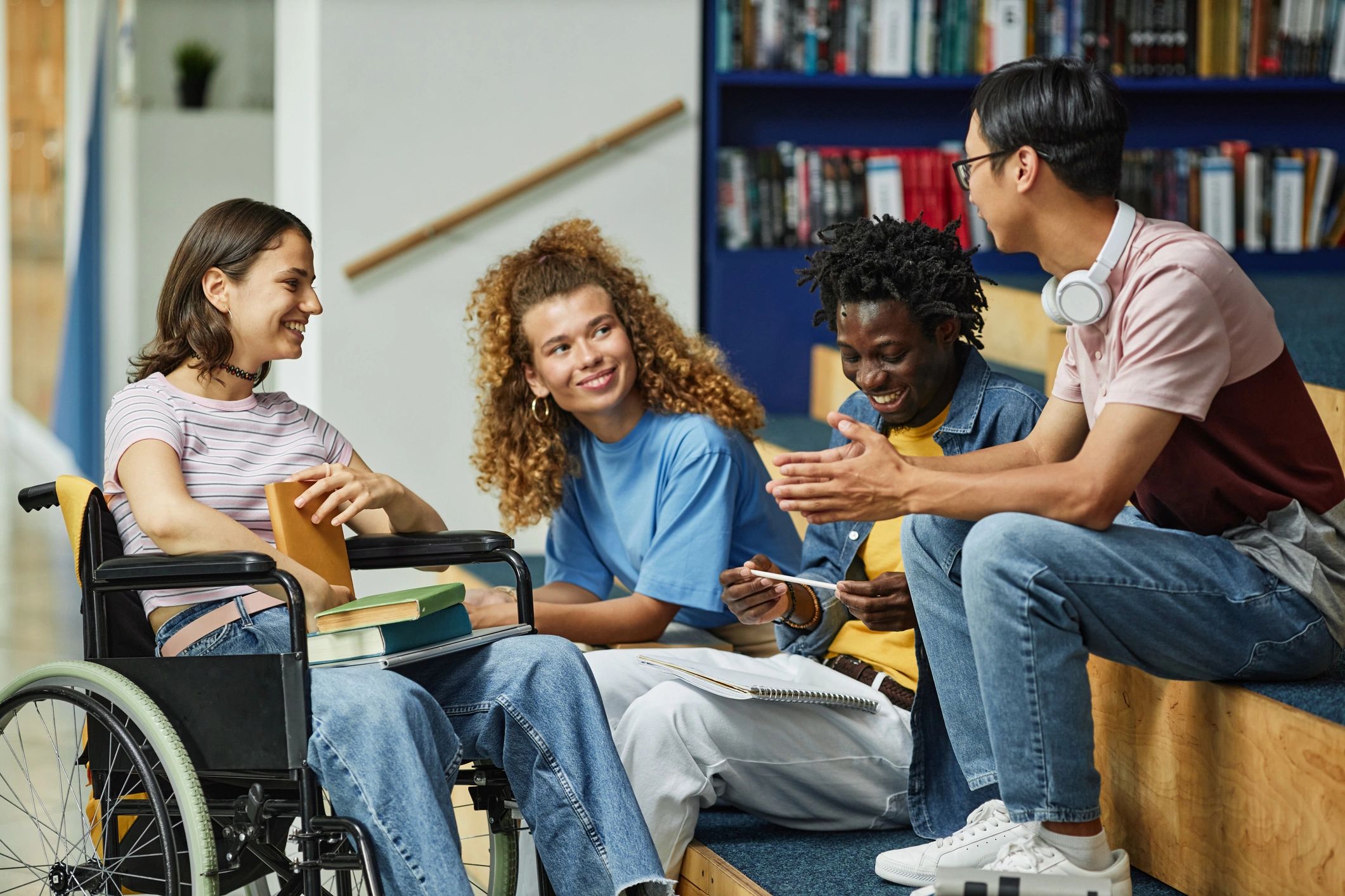 Diverse students chatting in a college library including a female student with a disability