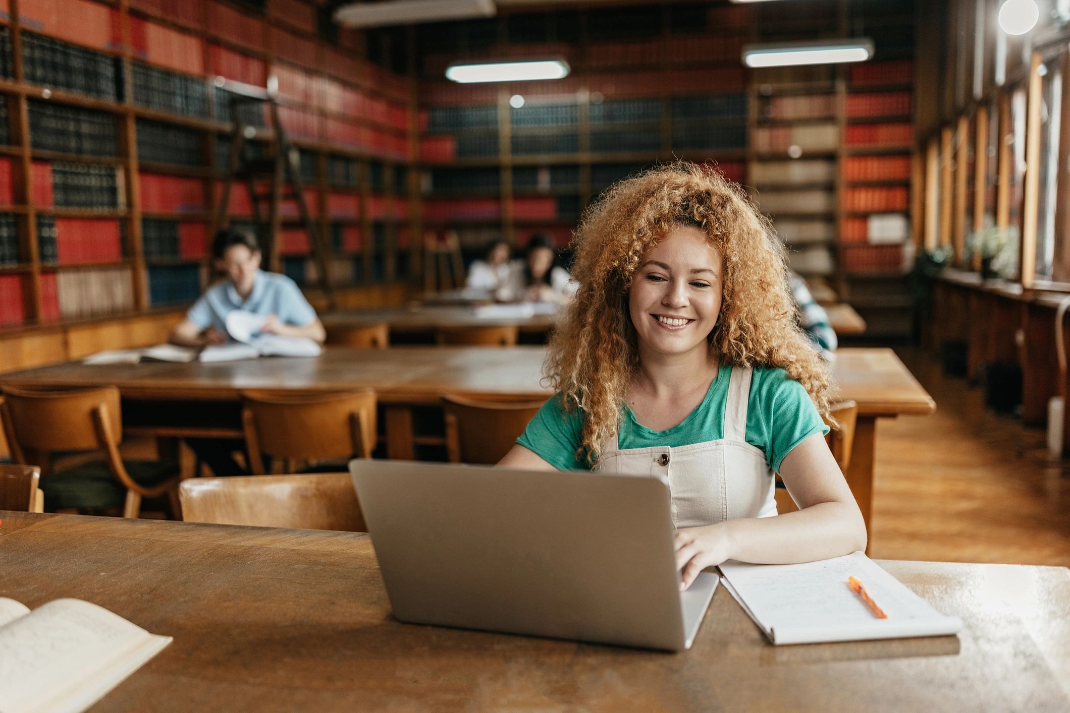 Student working on a laptop with other students nearby