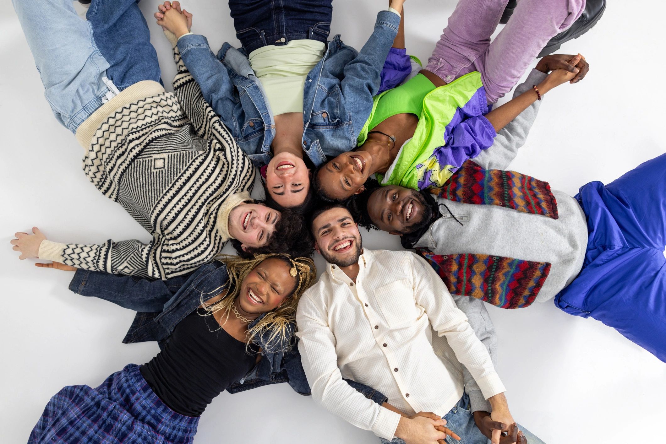 Young people lying in a circle holding hands and smiling