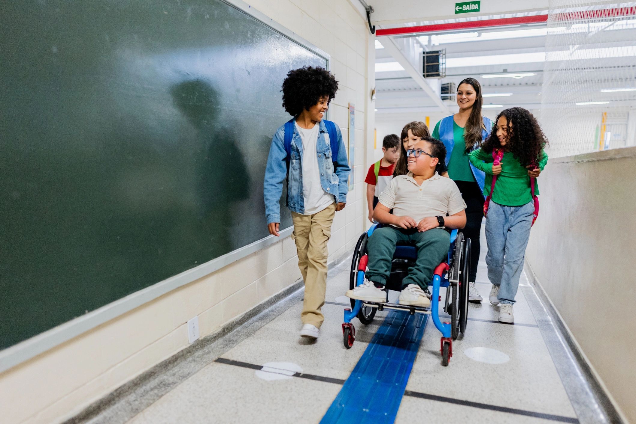 Students walking together in a school corridor, including a wheelchair user